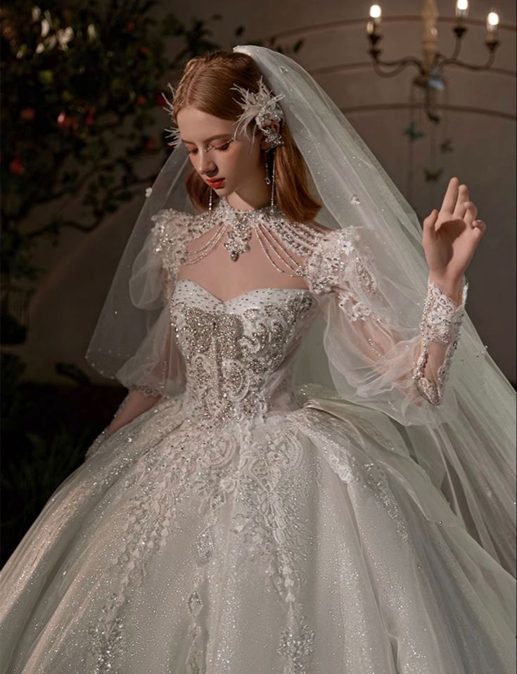 a woman in a white wedding dress with a veil on her head and hands up