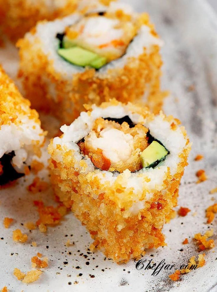 sushi rolls with cucumber and cheese are on a piece of parchment paper