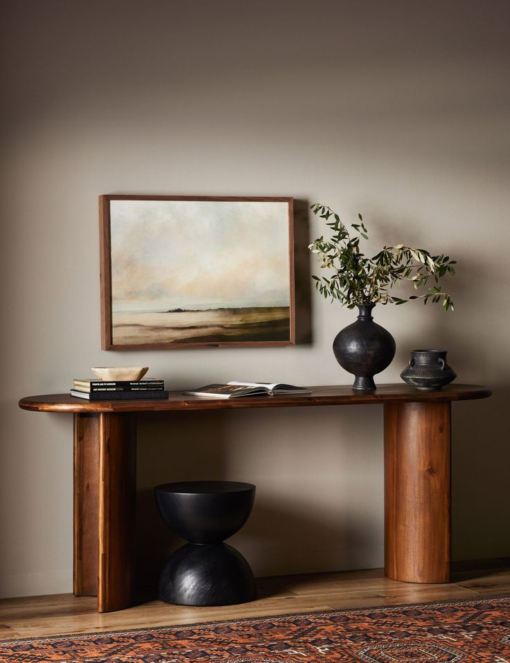 a table with two vases and a painting on the wall above it in a living room