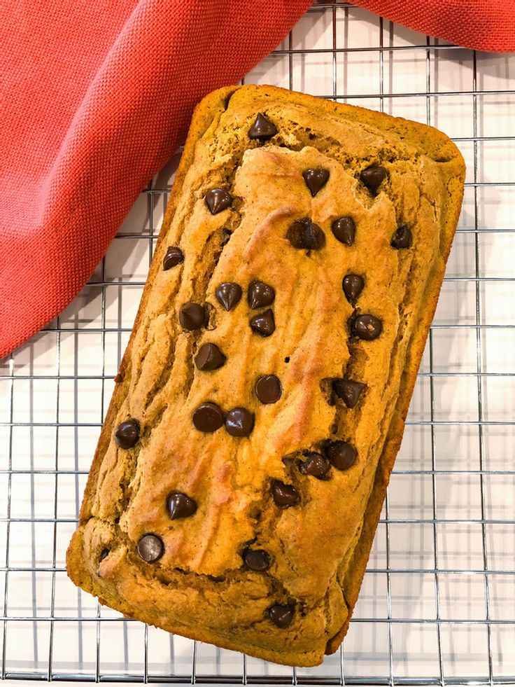 a loaf of chocolate chip bread sitting on top of a cooling rack next to a red napkin