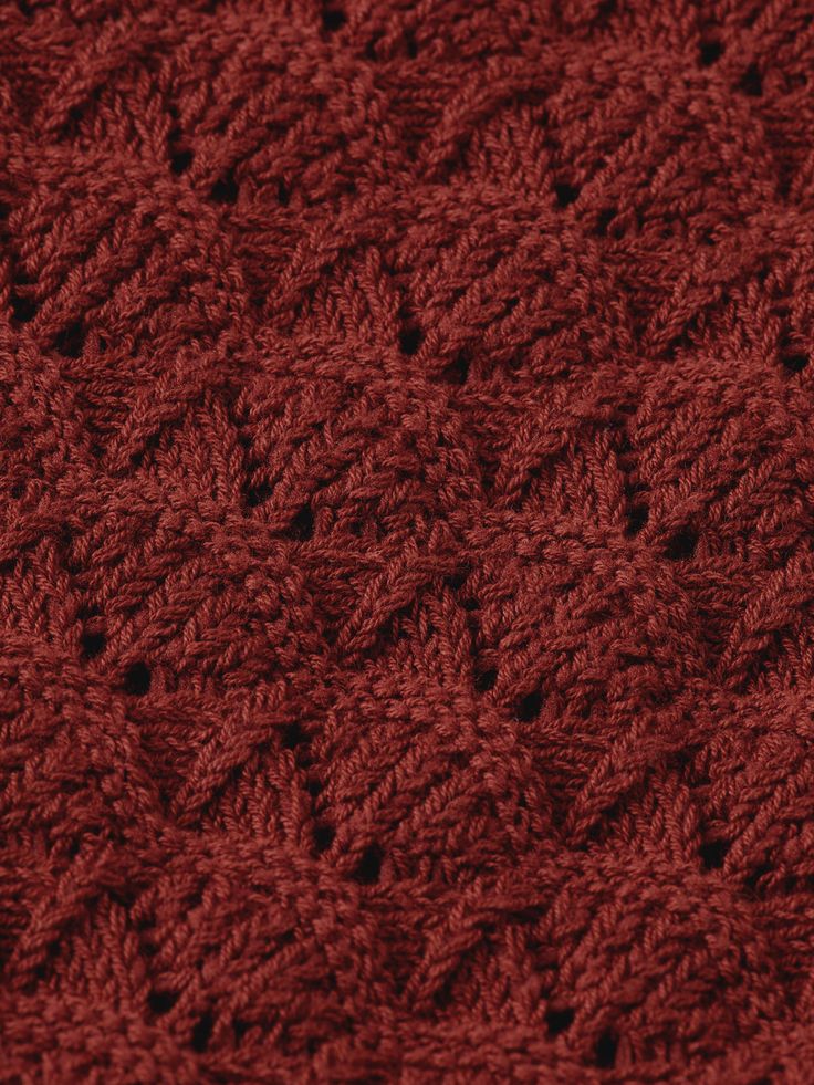 a close up view of a red knitted sweater with small leaves on the side