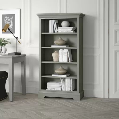 a living room with a chair, table and bookcase on the floor in front of a white wall