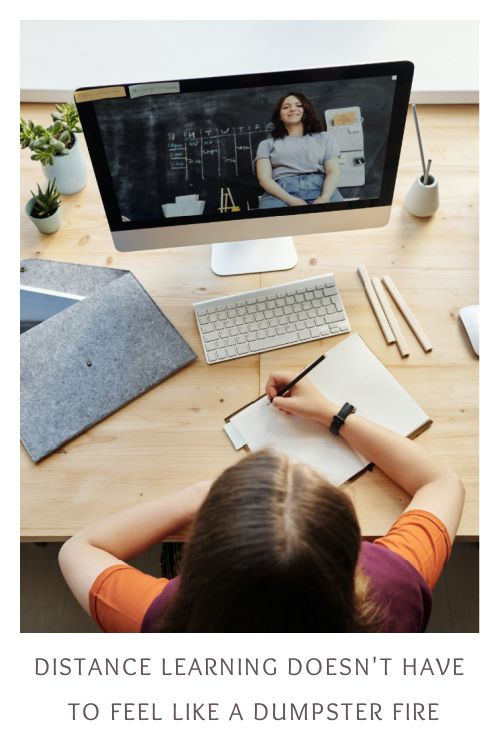 a person sitting at a desk with a monitor and keyboard in front of them, writing on a piece of paper