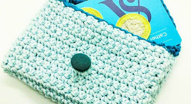 a crocheted blue wallet with a green button on the front and a credit card holder in the back