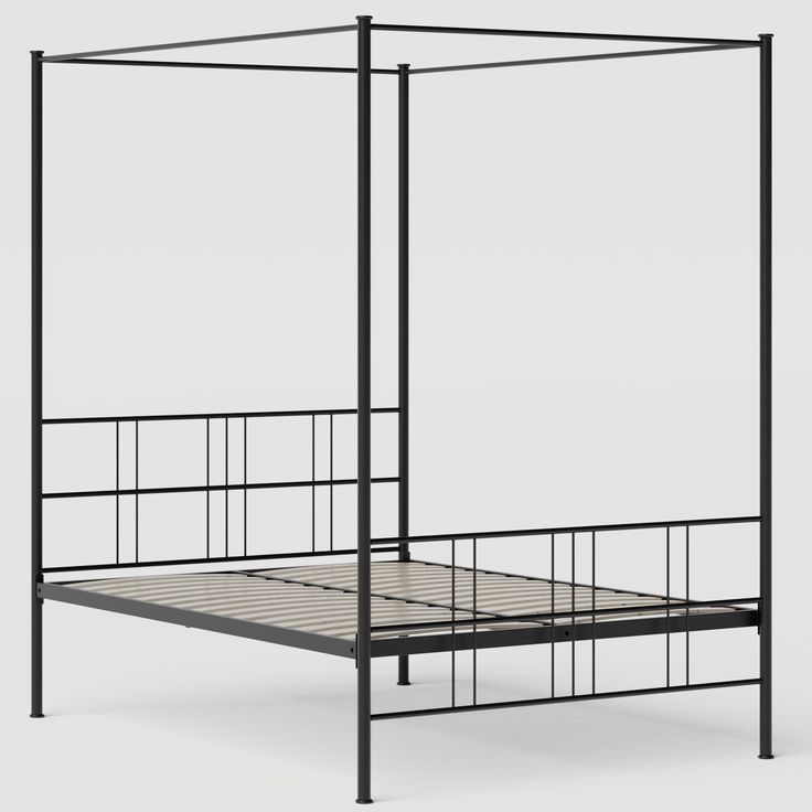 an iron bed frame with four posts and a mattress underneath it, viewed from the side