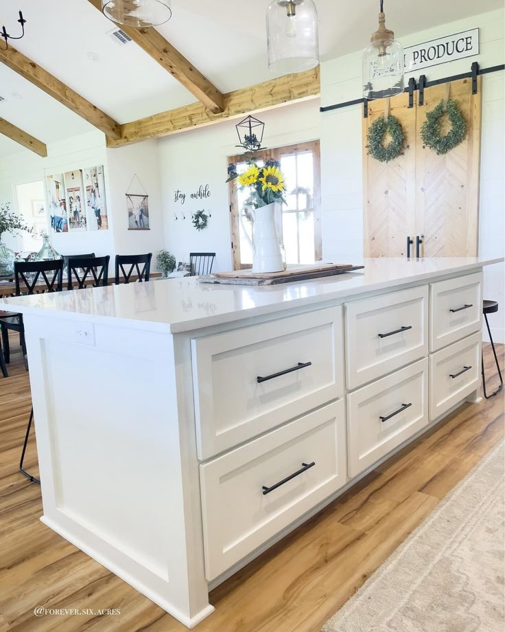 a large kitchen island with white cabinets and drawers in the middle of a wooden floor