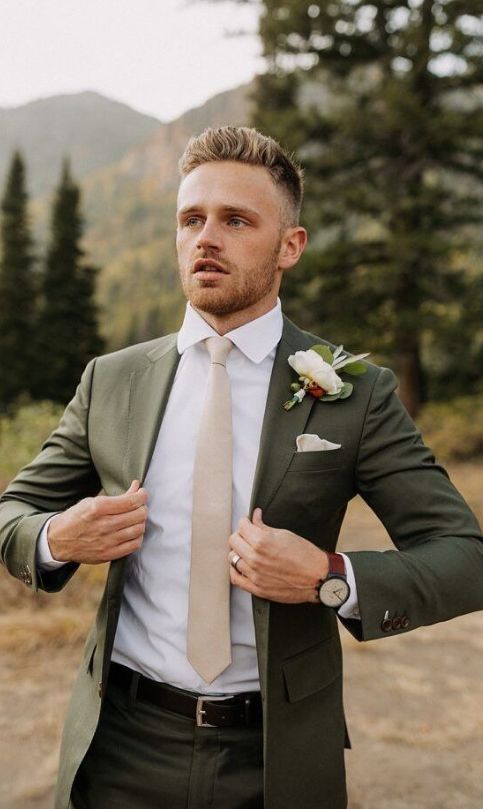 a man in a suit and tie is posing for the camera with his hands on his hips