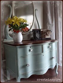 a blue dresser with flowers and a mirror on top