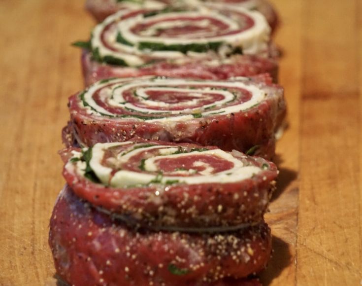 sliced up meatloaf rolls on a wooden cutting board with herbs and seasoning