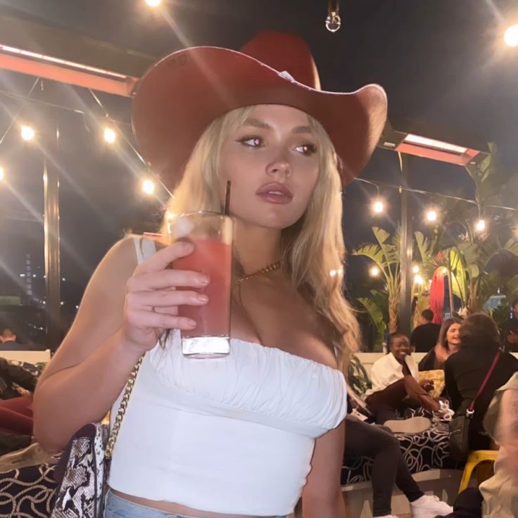 a woman wearing a cowboy hat holding a drink