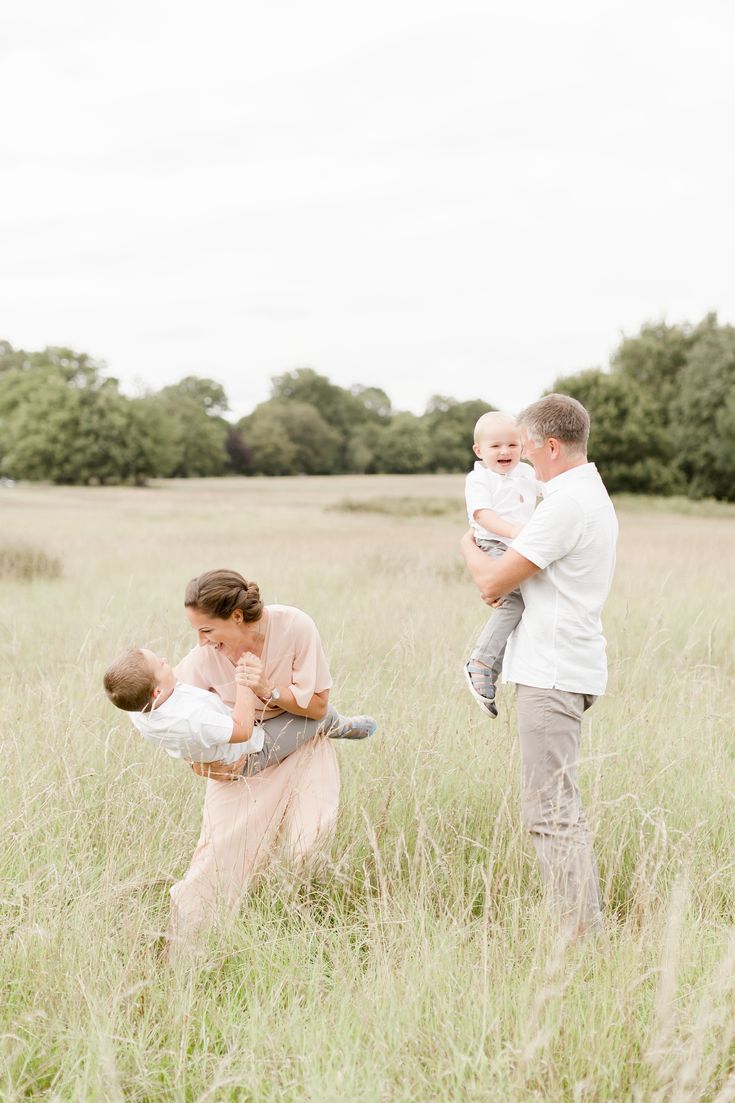 a man holding a baby while standing in a field with two women and a child