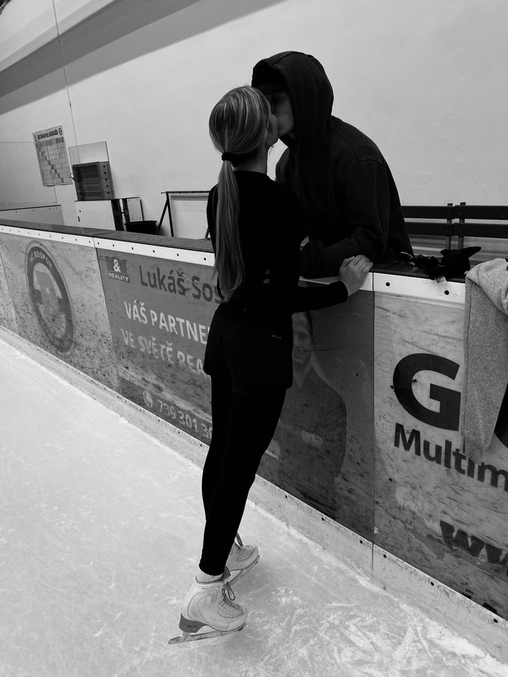 a man and woman kissing while standing on an ice rink at a mall in black and white