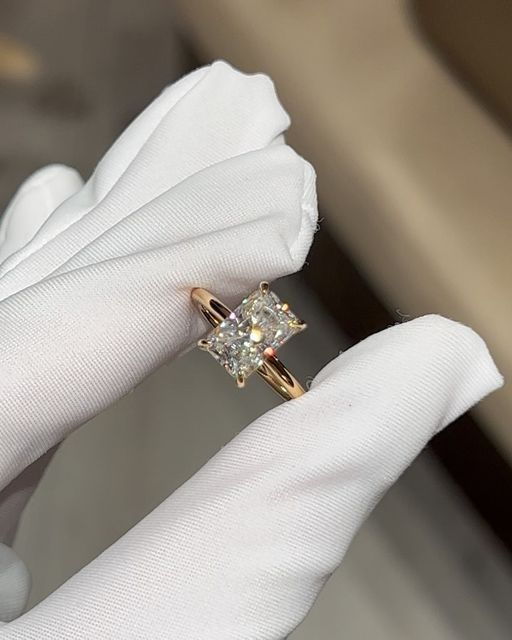 a close up of a person's hand holding a ring with a diamond in it