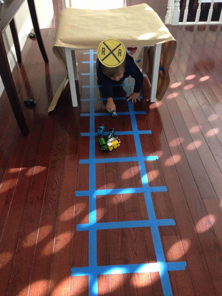 a young boy is playing with blue tape on the floor