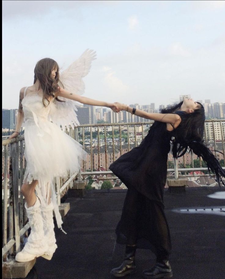 two women dressed in white and black are dancing on a balcony with cityscape in the background