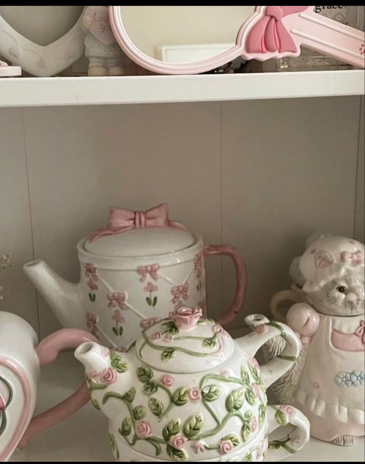 a shelf filled with pink and white teapots, dishes and other decorative items