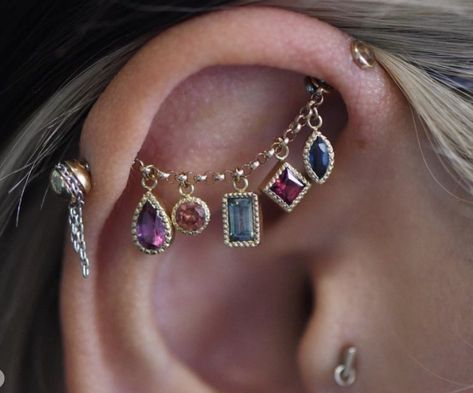 a woman wearing ear piercings with different colored stones