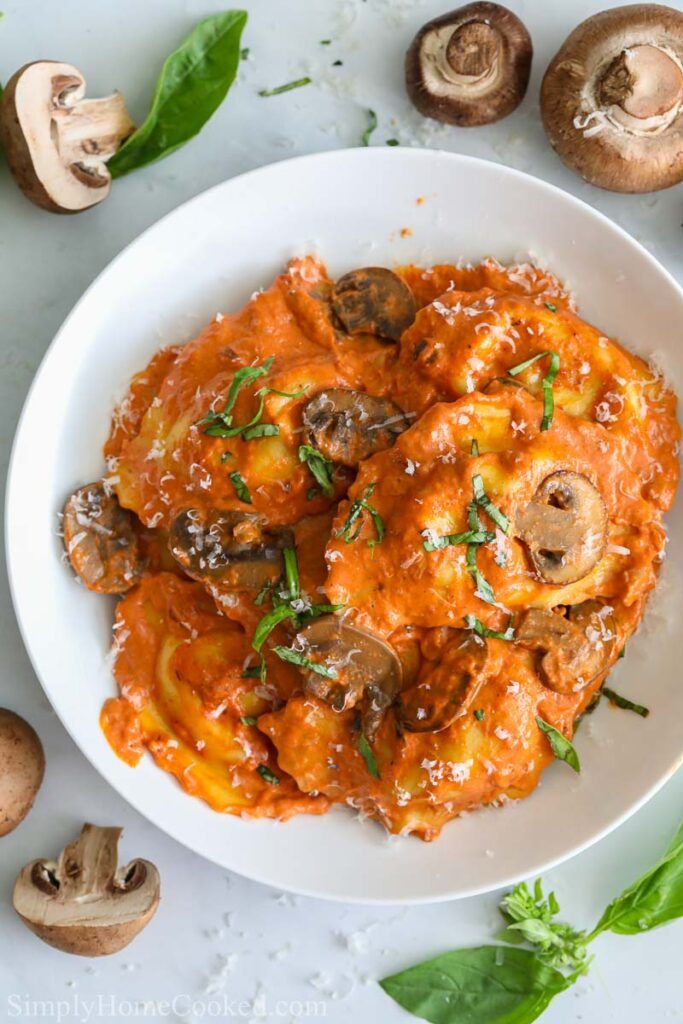 a white plate topped with pasta covered in mushroom sauce and garnished with parsley