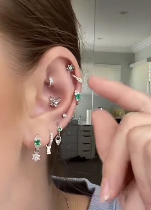 a woman is holding up her ear with three different piercings on top of it