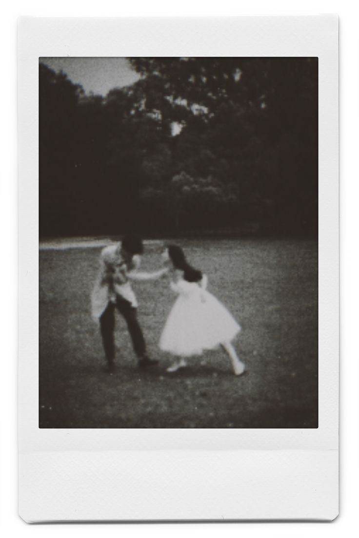 an old photo of two people in a field with one holding the other's hand