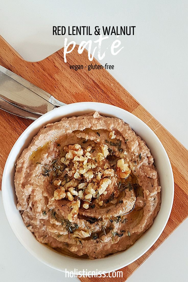 a white bowl filled with red lentil and walnut pate on top of a wooden cutting board