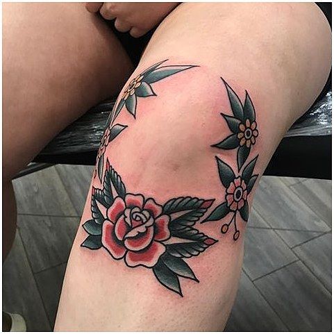 a woman's thigh with a rose tattoo on her left leg and the rest of her leg behind her