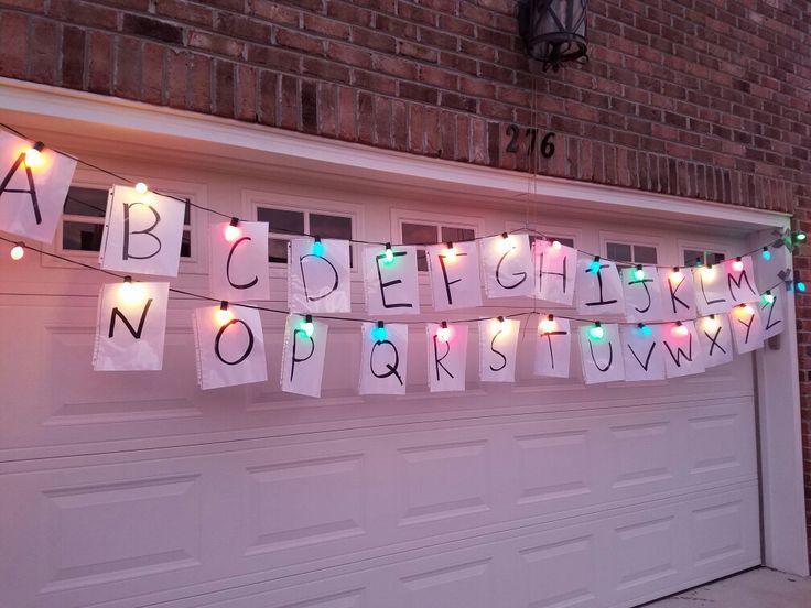 christmas lights strung from the side of a garage door with letters and numbers on them