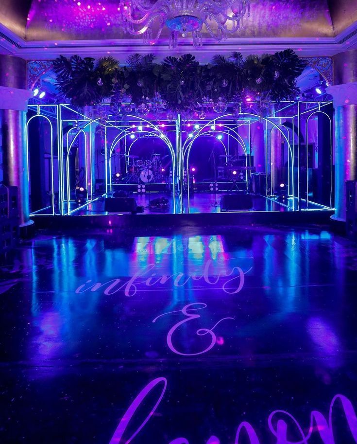 the dance floor is lit up with purple and blue lights