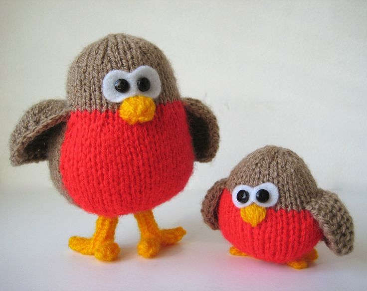 two knitted stuffed birds sitting next to each other on top of a white surface