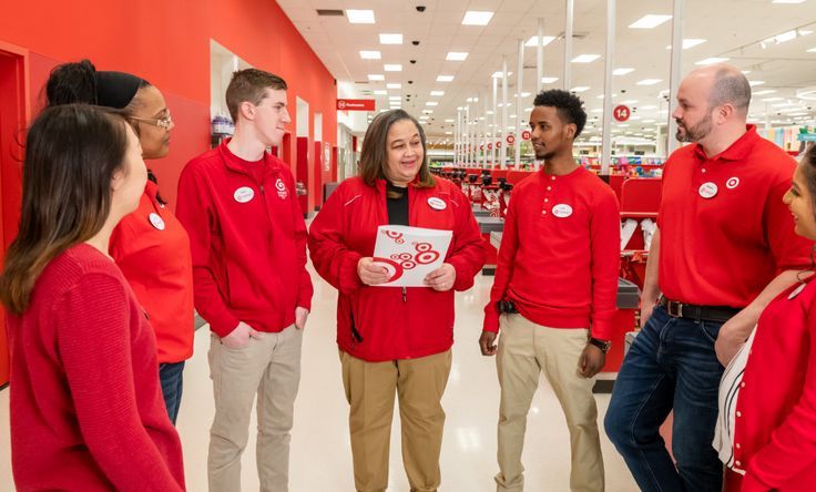 a group of people standing around each other in a store talking to one another and smiling