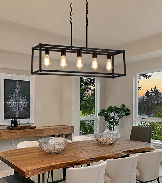 a dining room table with white chairs and lights hanging from it's center beam