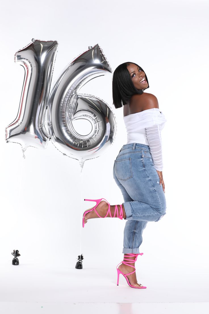 a woman standing in front of a balloon with the number sixteen on it and wearing high heels