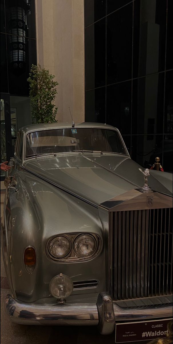 an old car is parked in front of a building