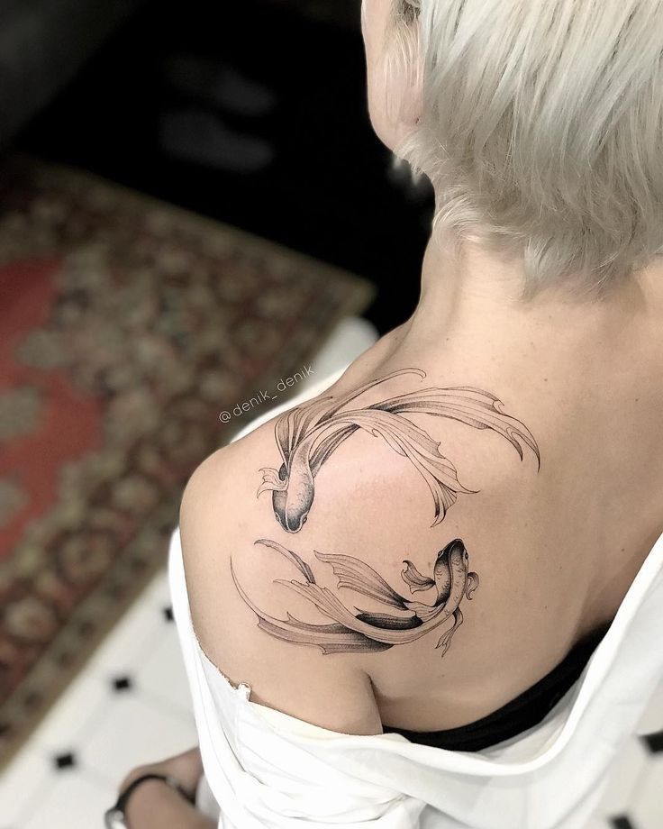 the back of a woman's shoulder with a horse and fish tattoo on it