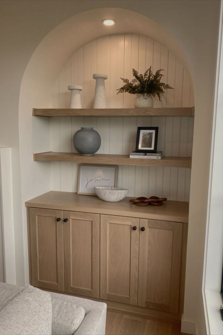 a living room with some shelves and vases on top of it's cabinets