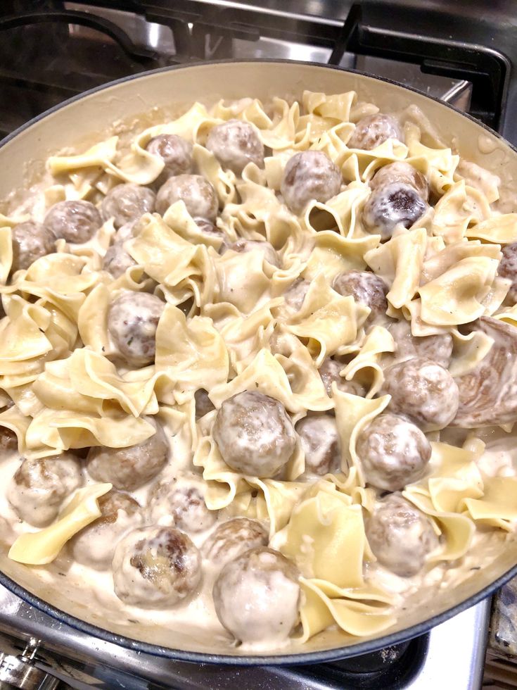 a pan filled with pasta and meatballs on top of a stove