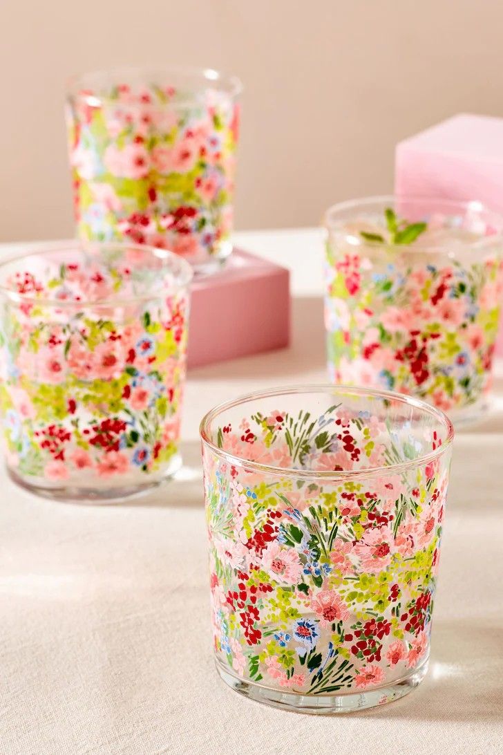 four floral glass votives sitting on a table next to a pink tissue box