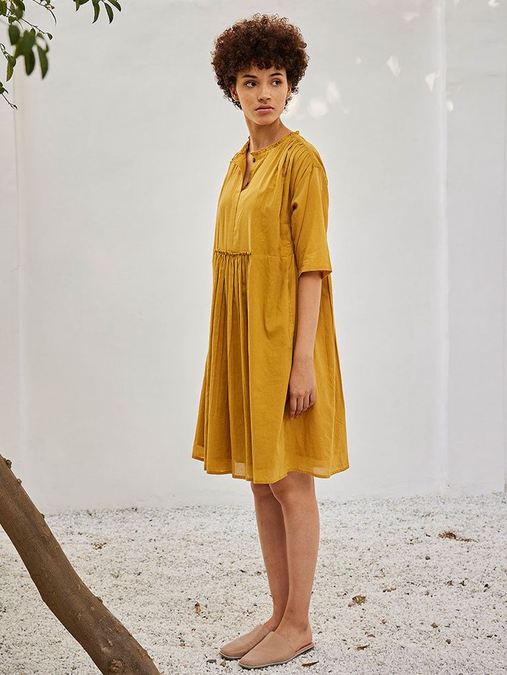 VALUES Handcrafted Organic Fair Minimal Waste CURATOR'S NOTE Crafted from mulmul cotton, this dress comes with attached gathered panels at the front and the back, ruffles at the neckline, front button opening and gathers at the shoulder. It comes with side seam pockets and is fully lined. THE DESIGNER STORY KHARA KAPAS, meaning 'pure cotton' in Hindi, started with the belief that design is a form of expression. True to its name, the brand continuously strives to achieve purity through their fabr Casual Dresses With Gathered Neckline For Gatherings, Cotton Daywear Dress With Gathered Sleeves, Cotton Day Dresses With Gathered Sleeves, Relaxed Fit Smock Dress For Daywear, Cotton Smock Midi Dress For Daywear, Cotton Daywear Dress With Gathered Neckline, Cotton Dresses With Gathered Waist And Short Sleeves, Cotton Smocked Midi Dress, Knee-length Dress With Gathered Waist For Daywear