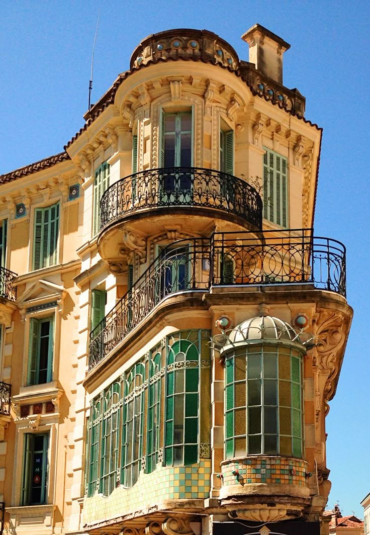 an old building with balconies and green shutters on the top floor is shown in front of a blue sky