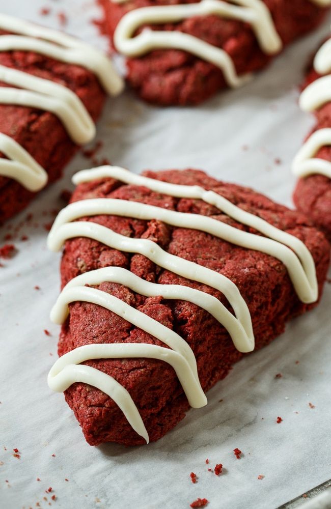 red velvet cookies with white icing are on a baking sheet and ready to be eaten