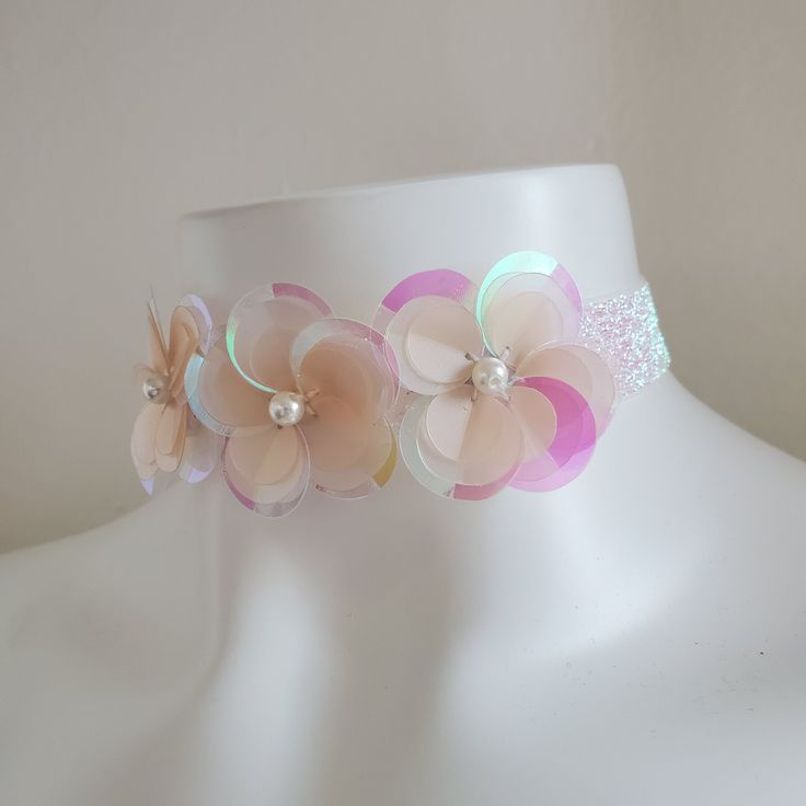 This cute floral choker necklace is the perfect accessory to finish your sparkly outfit! It adds the final touch to rave and music festival outfits, unicorn looks, sparkly fairy outfits, and pairs perfectly with our sequin kimonos. This choker is made of lightweight white iridescent elastic. There are three sequin flowers, hand sewn onto the necklace right here in our Los Angeles studio. It is adjustable with a back hook and chain. DETAILSLength: 12" (adjusts up to 20")Width: 1" SHIPPINGShips fr Summer Pink Choker As Gift, Adjustable Rave Choker For Gift, Adjustable Rave Choker For Gifts, Adjustable Multicolor Choker For Parties, Adjustable Rave Choker As Gift, Adjustable Multicolor Party Choker, Bohemian Summer Party Choker, Adjustable Pink Choker For Festivals, Handmade Rave Jewelry For Party