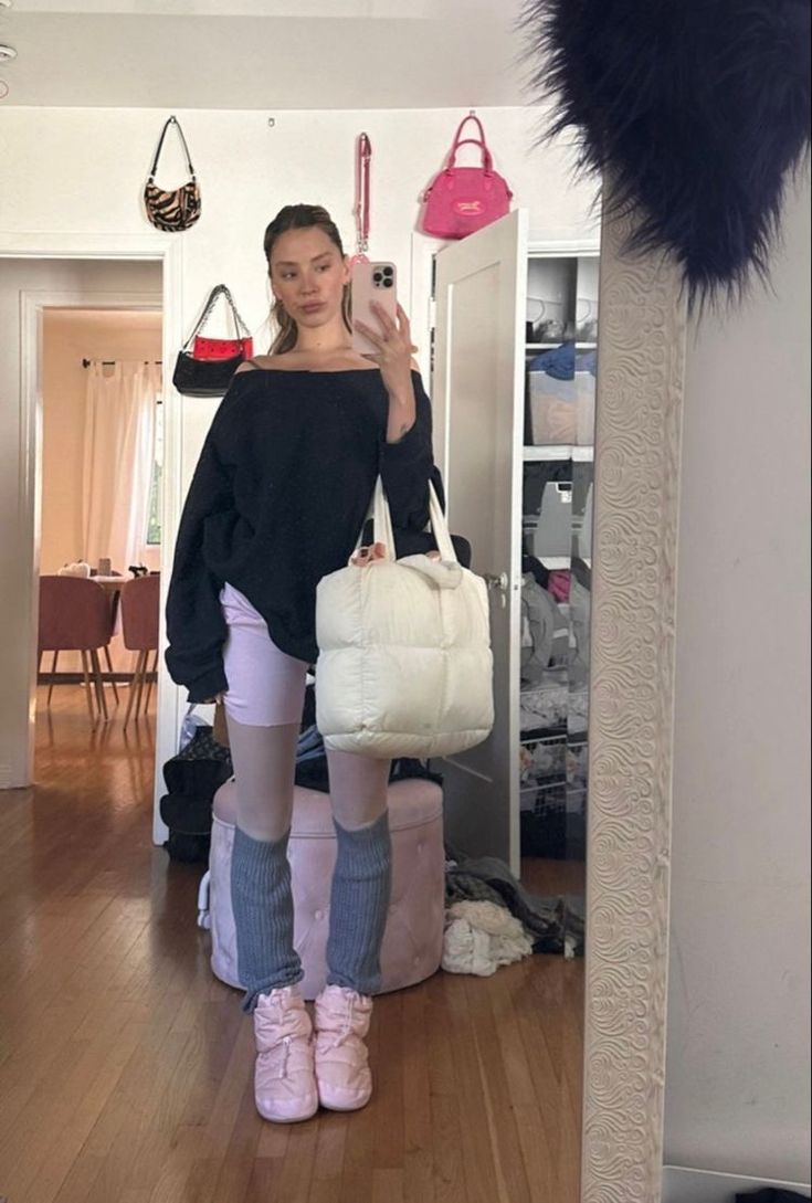 a woman standing in front of a mirror holding a white bag and wearing pink shoes