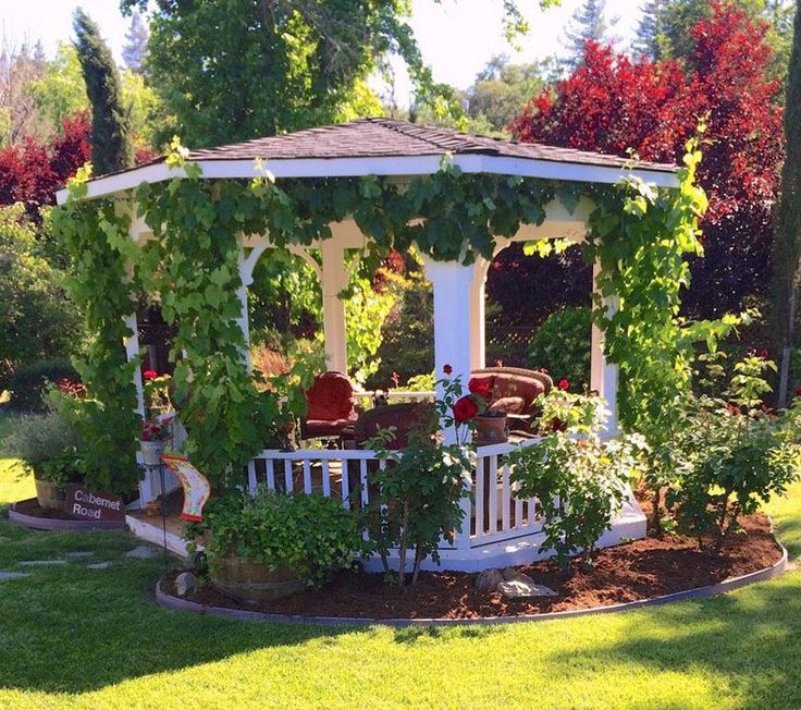 a white gazebo surrounded by flowers and greenery