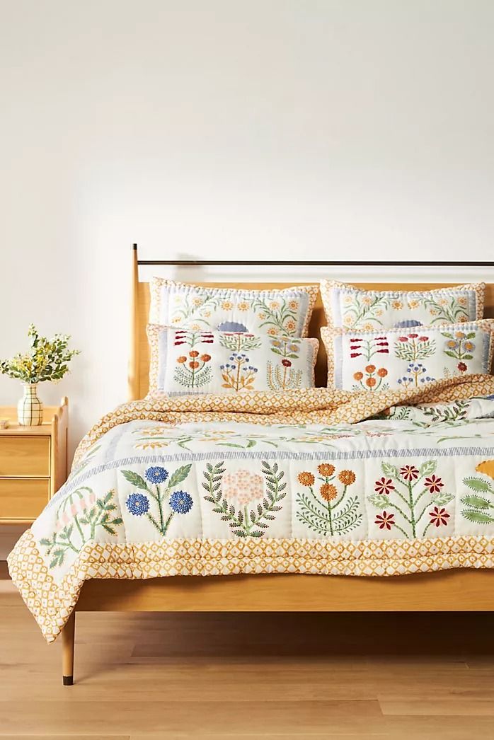 a bed with white and blue flowers on the comforter, pillows and pillow cases