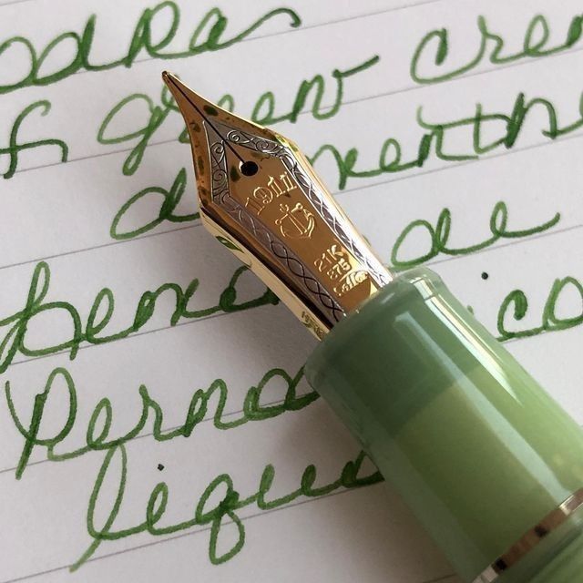 a green fountain pen sitting on top of a piece of paper with cursive writing