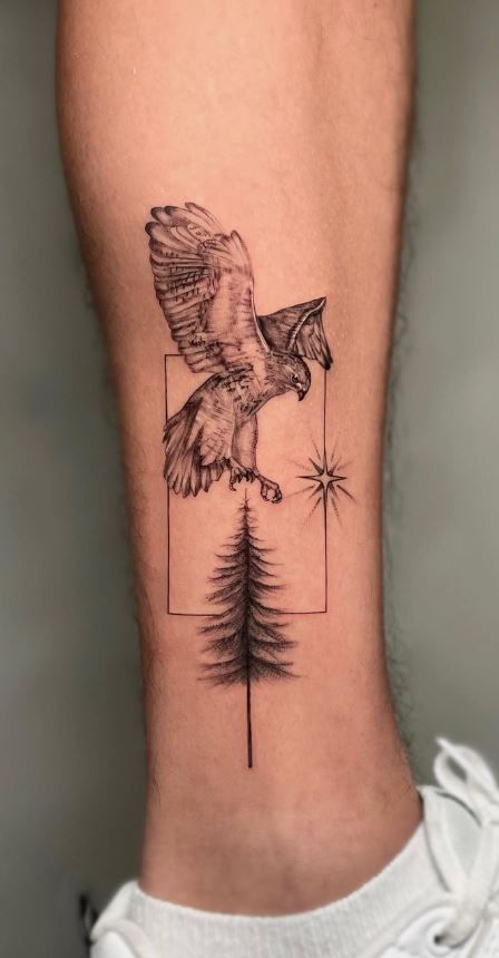 an eagle and pine tree tattoo on the back of someone's left leg,