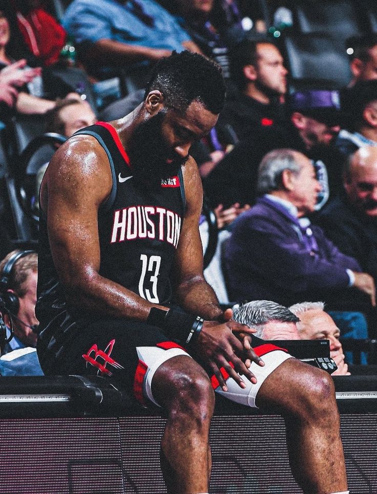 a man sitting on top of a bench in front of a group of people at a basketball game