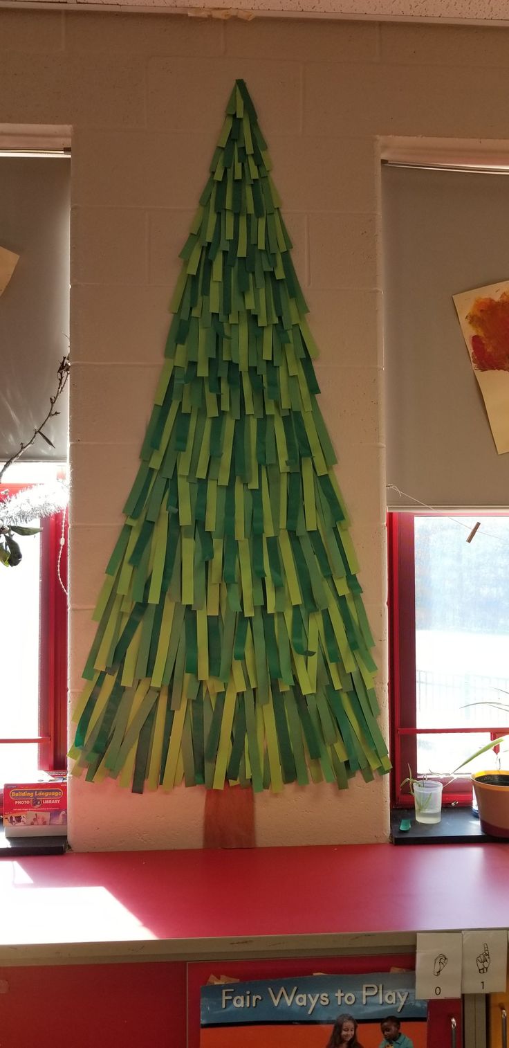 a christmas tree made out of strips of paper on top of a shelf in front of a window