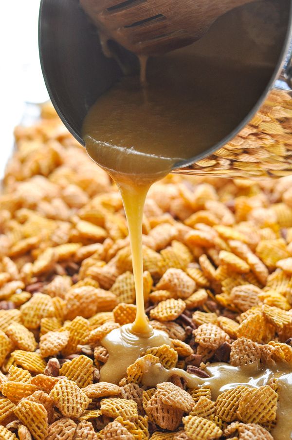 a person pouring peanut butter into a bowl of cheetos