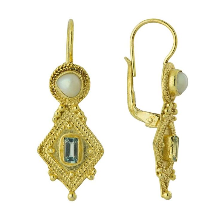 a pair of gold earrings with an aqua blue stone in the center and a white bead